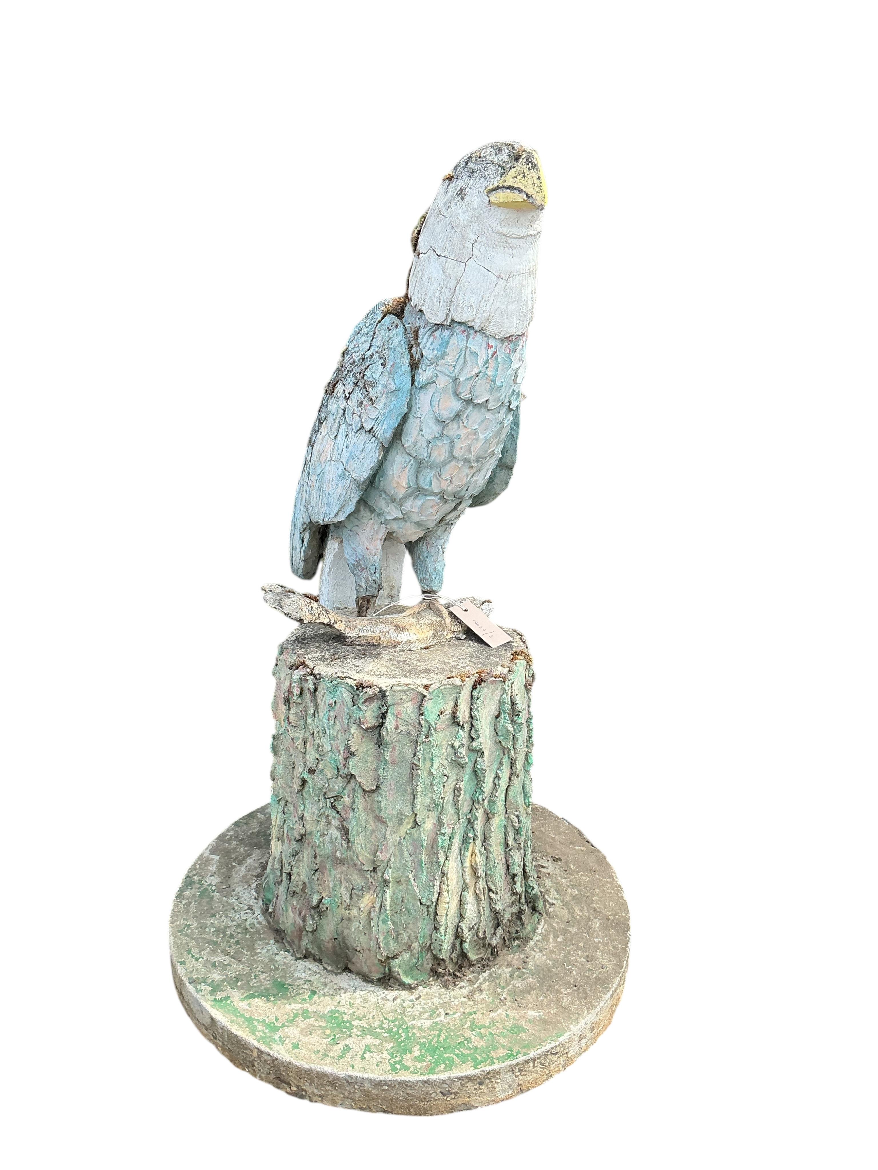 A cast stone garden ornament of an eagle perched on a stump with a salmon in its talons, on square wood plinth, height 150cm